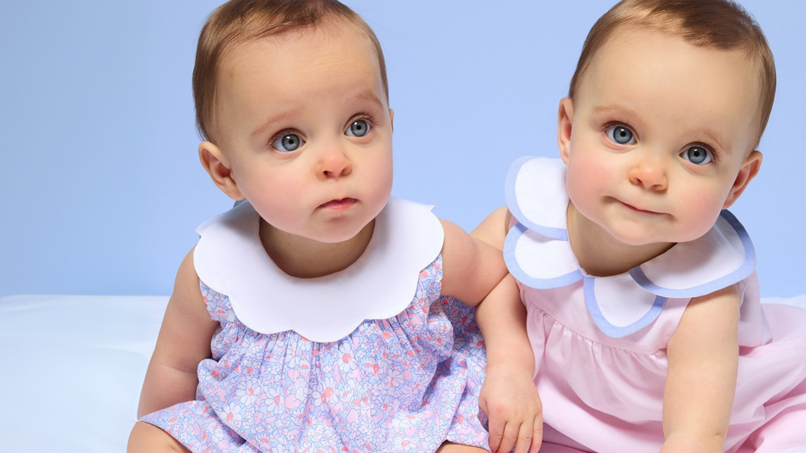 Soft cotton newborn baby clothes laid out on white bedding, featuring luxury baby clothes essentials from Jacadi